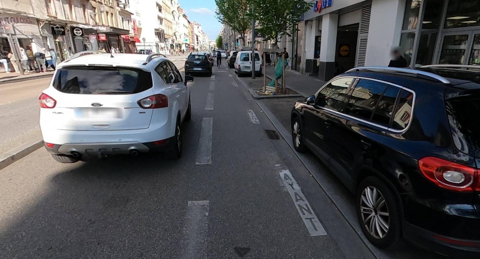Bande cyclable sur le cours Lafayette à Lyon. Les cyclistes sont coincés entre les voitures en stationnement et la circulation motorisée.